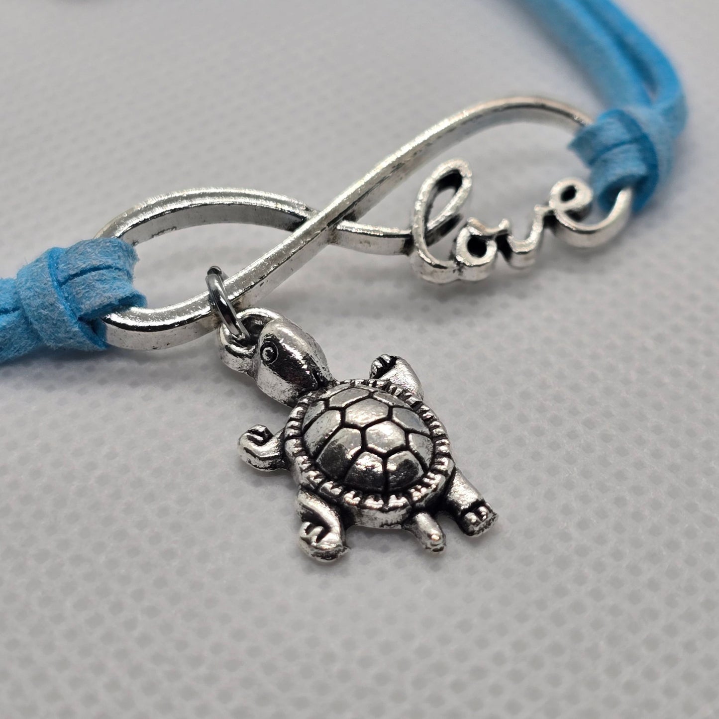 Close-up image of the turtle charm on the Infinite Love for Turtles bracelet, featuring intricate detailing on the infinity symbol and charm.