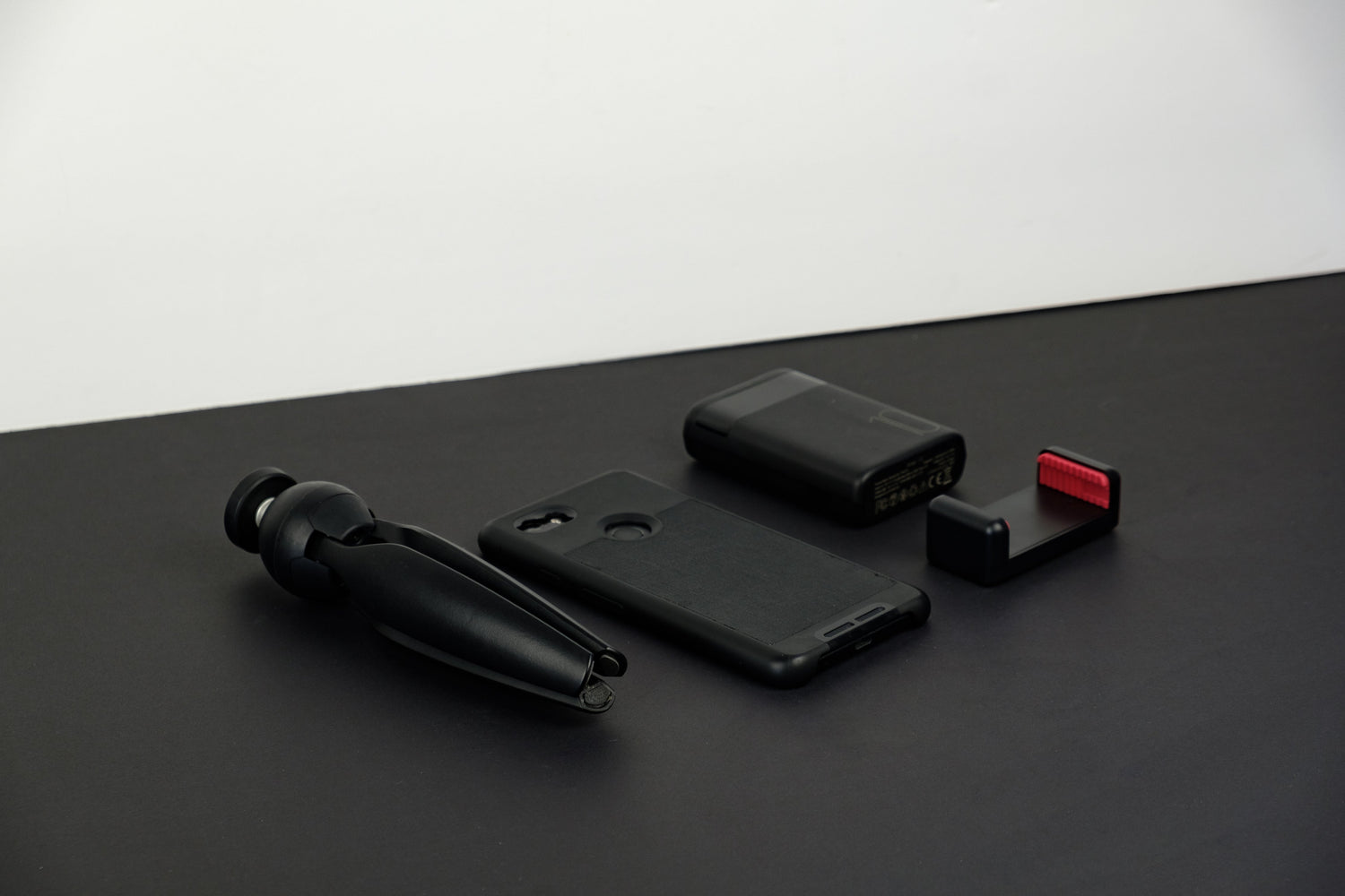 Phone accessories including a compact tripod, protective phone case, portable charger, and phone mount, ideal for enhancing mobile functionality and protection.