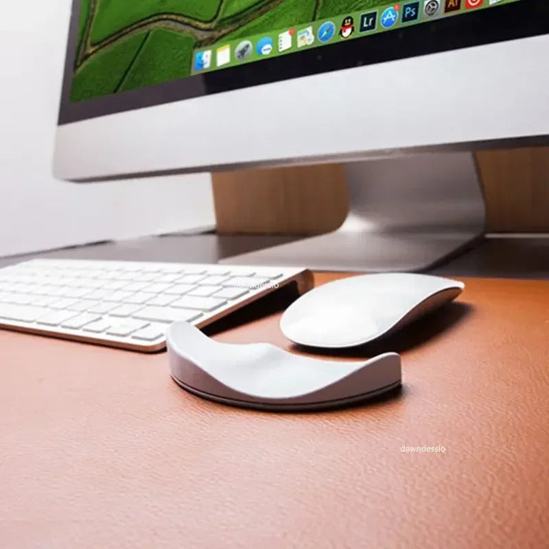 Gray ergonomic mouse pad wrist rest placed next to a keyboard and mouse on a modern office desk.