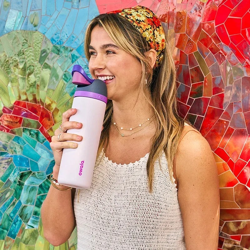 Woman drinking from stainless steel tumbler with built-in straw and flip-top lid.